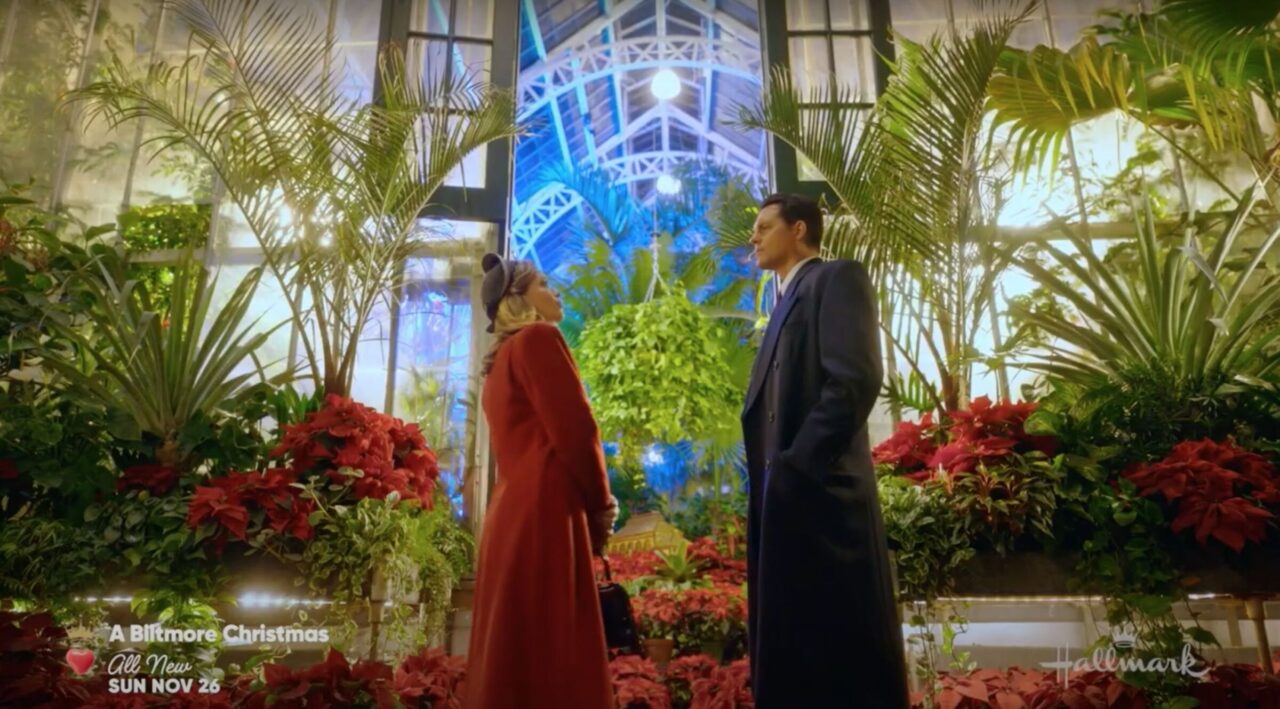 A man and a woman in the Winter Garden at Biltmore Estate in a scene from Hallmark Channel's "A Biltmore Christmas."